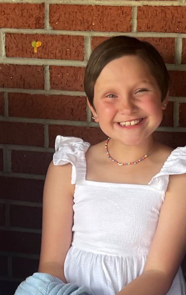 Olivia Reardon smiles at the camera while standing in front of a brick wall. 