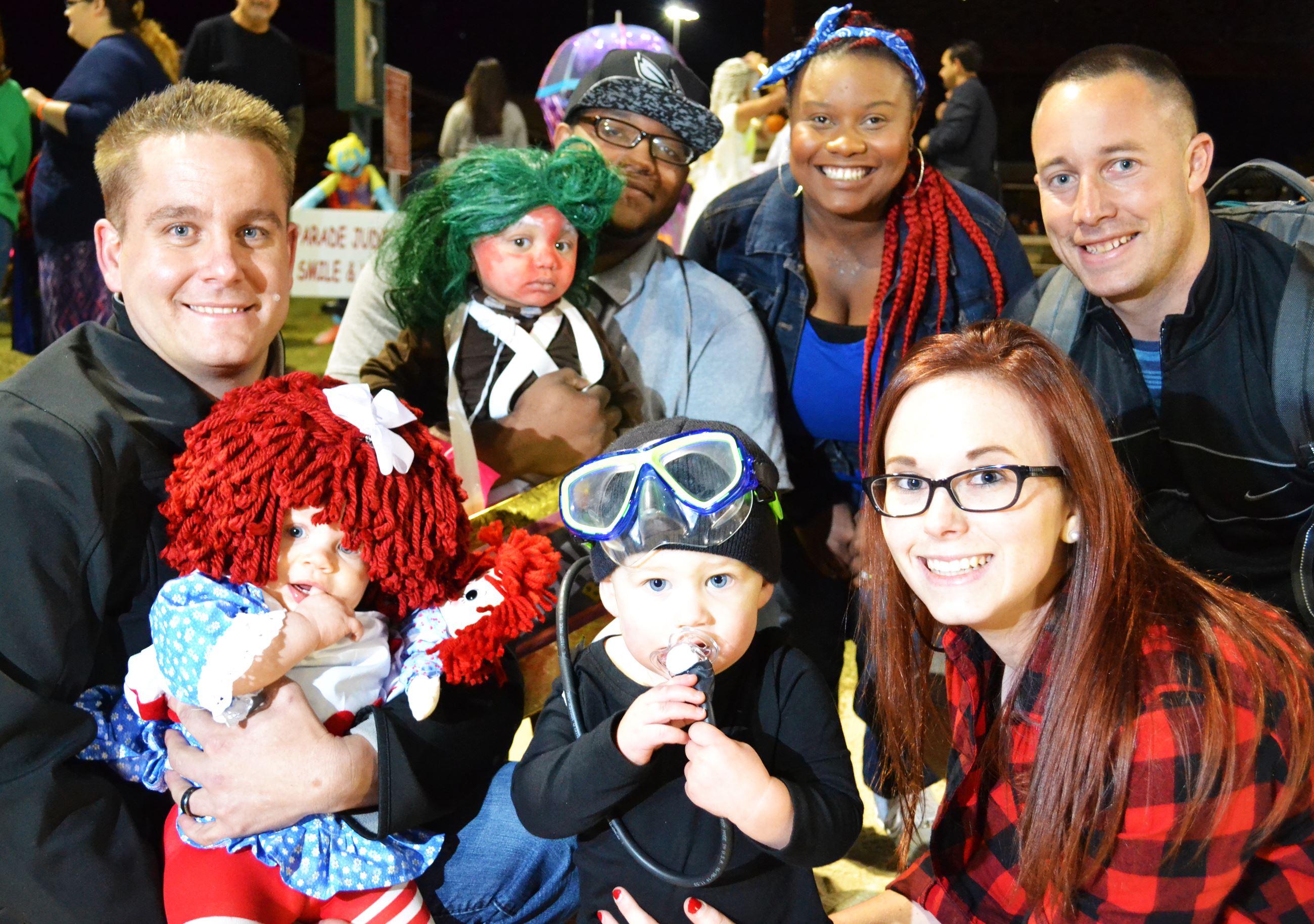 Families pose in their Halloween costumes.
